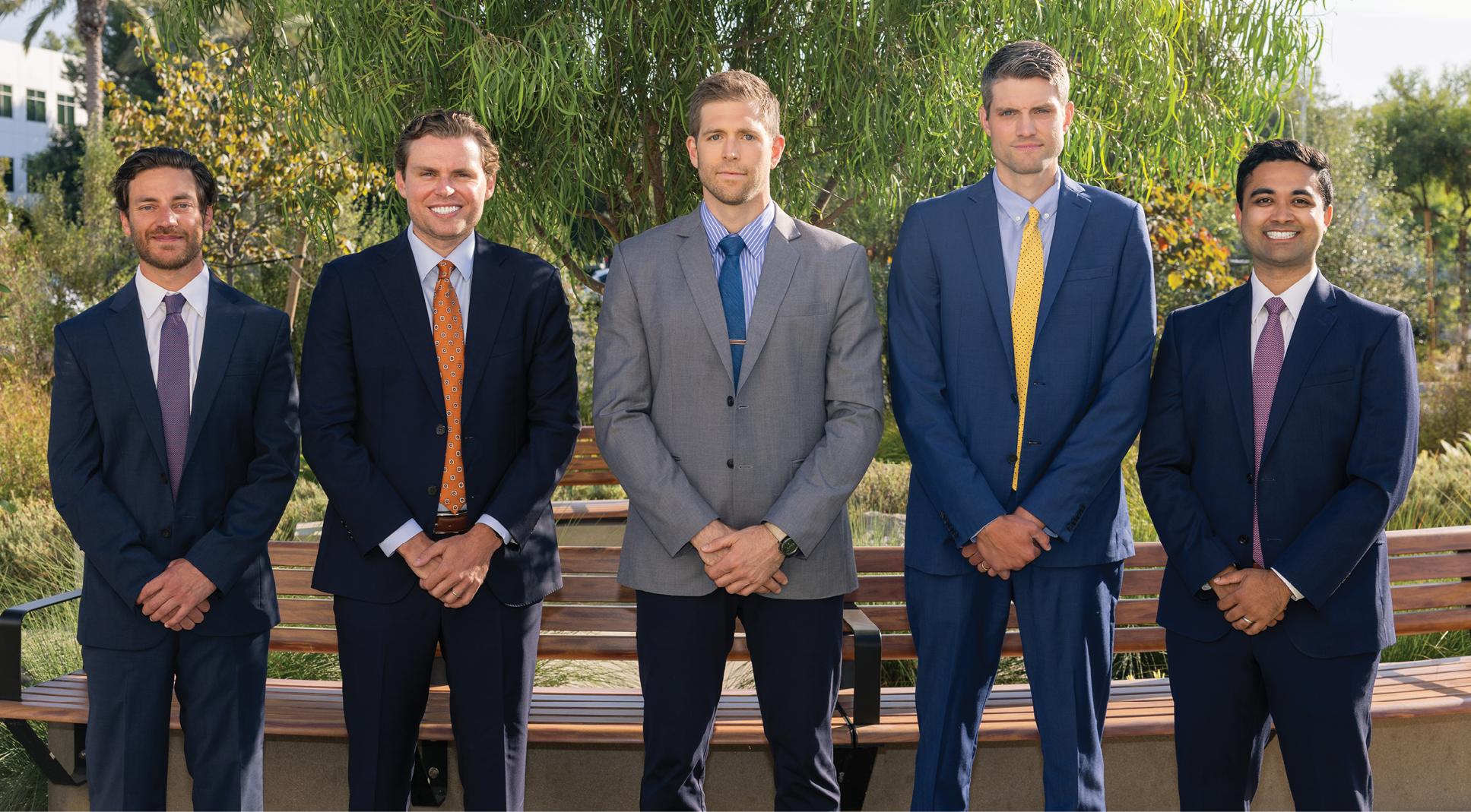 group of five men in various color suits and ties