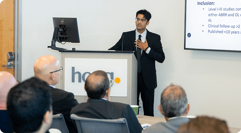 medical student behind podium, wearing dark suit with white shirt